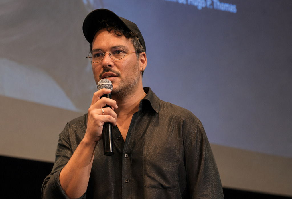 Hugo Thomas speaking on stage with a microphone